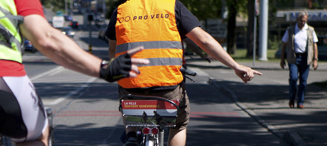 Un homme sur un vélo; il porte un gilet "pro vélo"