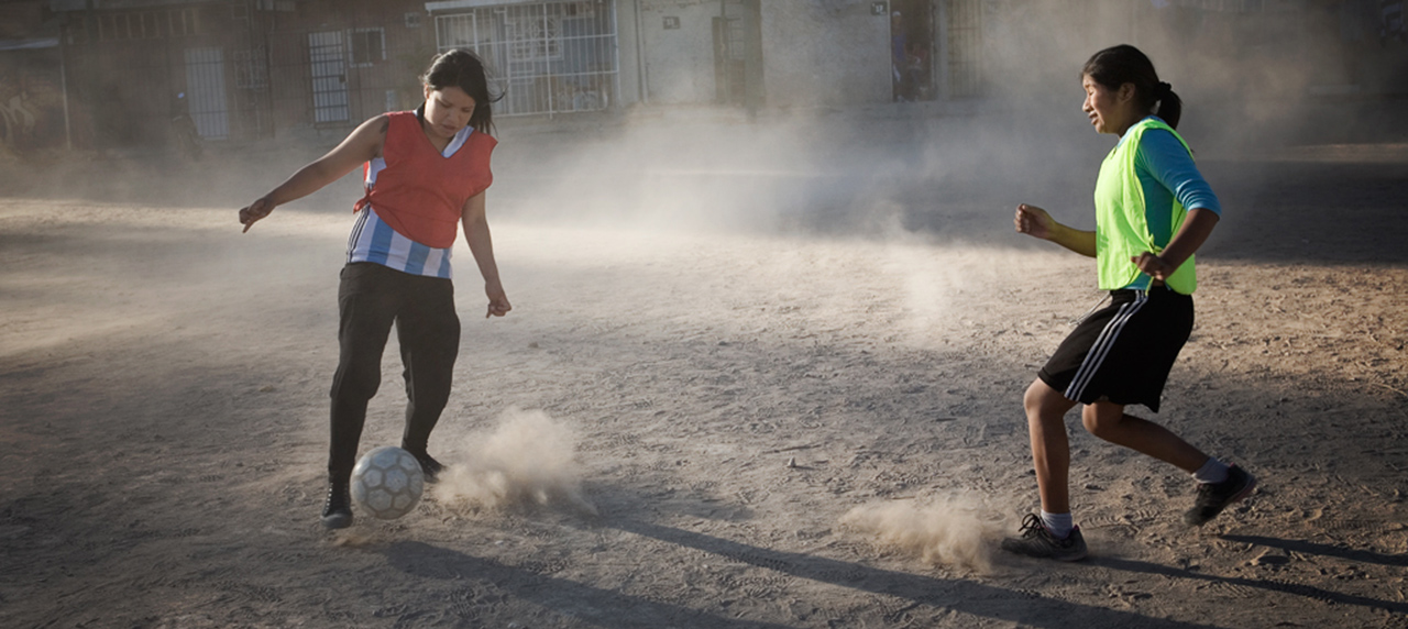 filles jourant au foot dans la poussière