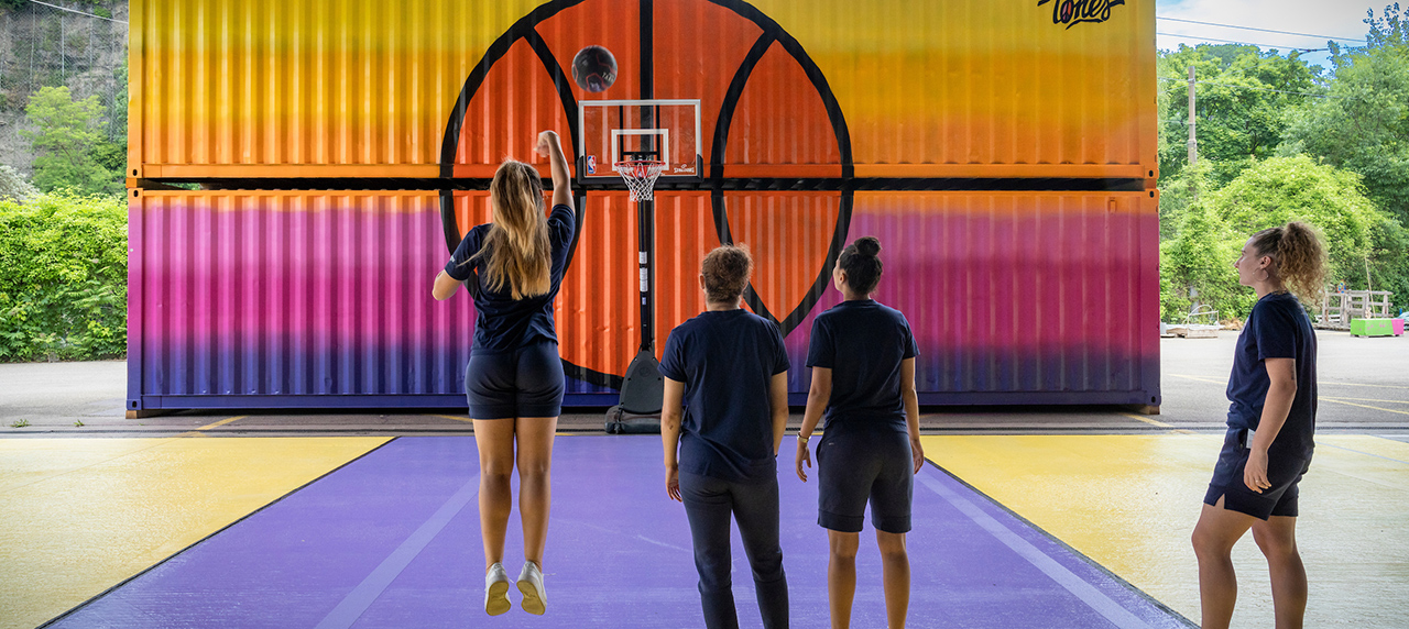 personnes jouant un basket contre un mur coloré