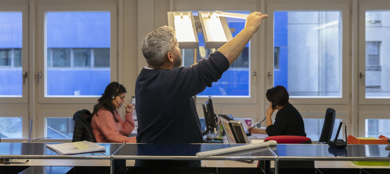 Un technicien change une ampoule dans un bureau