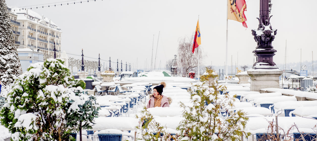 Une femme dans la neige sur une terrasse du quai du Mont-Blanc