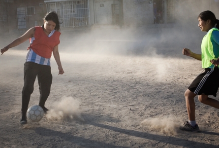 filles jourant au foot dans la poussière