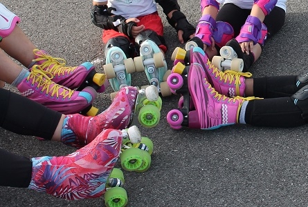 jambes d'enfants qui portent des patins à roulettes roses