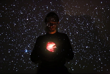 Photo d'un jeune homme avec un ciel étoilé en surimpression tien une limière dans ses mains.