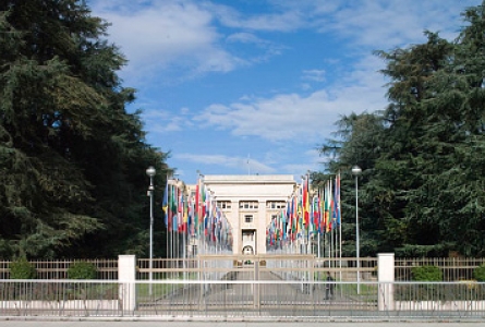 Entrée du Palais des nations, bordée de drapeaux et menant au bâtiment principal au fond