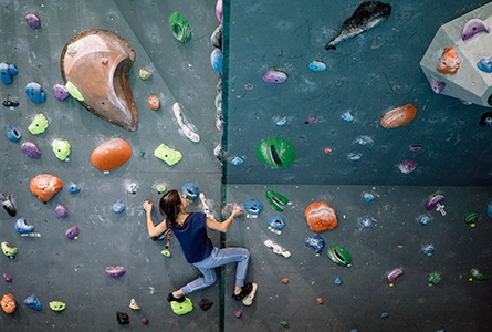 Une jeune fille grimpe sur un mur d'escalade dans une salle de sport