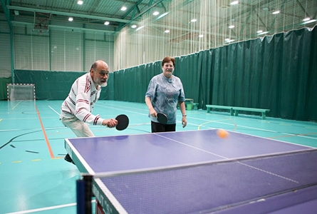 Des seniors jouent au tennis de table dans une salle de sport