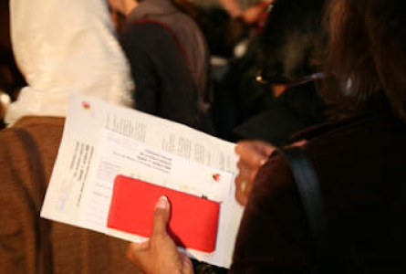 Une femme noire tient un livret rouge et des documents liés à la naturalisation suisse.