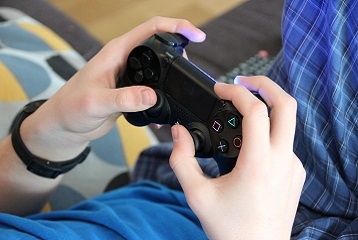 mains tenant une console de jeu vidéo