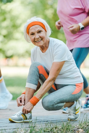 Une femme senior rattache son lacet durant son jogging