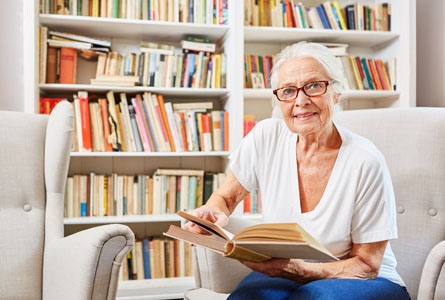 Une femme senior avec un livre assise dans un salon