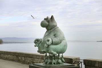statue de chat qui prend une pause de yoage devant le lac