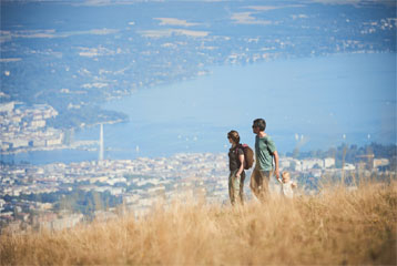 Un couple et son très jeune enfant se baladent sur le Salève et admirent la vue sur Genève.