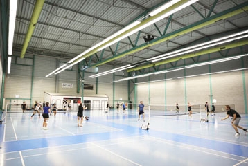 vue d'une grande salle avec personnes qui jouent au badminton