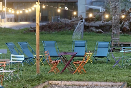 chaises et tables sur l'herbe avec guirlandes lumineuses au-dessus