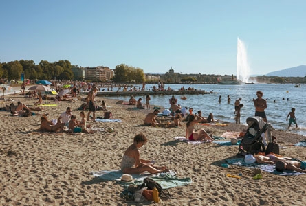 sable et personnes en maillot de bains au bord du lac avec le Jet d'eau en fond