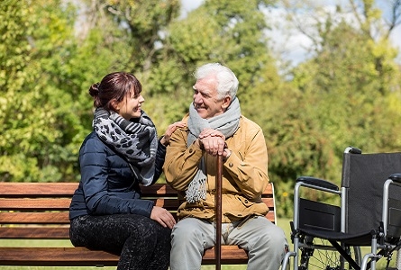 feme assise sur un banc qui met sa main sur l'épaule d'un homme plus âgé aux cheveux blancs