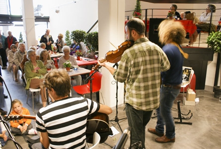 Vue d'une scène avec des musiciens de dos, jouant pour une assistance de personnes d'âge mûr