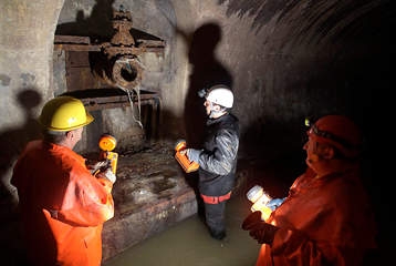 Des ouvriers contrôlent un collecteur d'eau dans une conduite souterraine.