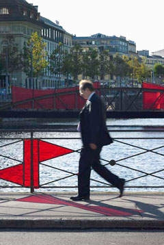 Un homme d'affaires traverse un pont avec des immeubles anciens en arrière-plan.