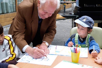 Un homme d'âge mûr fait un dessin devant deux petits enfants très attentifs.