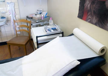 Un cabinet médical équipé d'un lit et de divers petits moyens.
