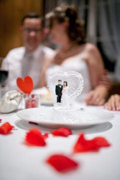 Lors de leur cérémonie de mariage, un jeune couple rie devant des figurines les représentant.
