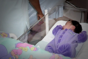 Un nouveau-né dort paisiblement dans la chambre d'hôpital de sa maman.