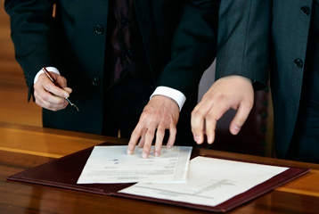 Des mains d'hommes signant les papiers de partenariat.