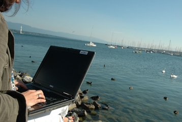une femme sur son ordinateur face au lac.