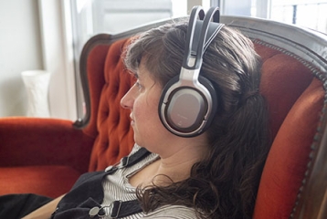 femme assise dans un canapé, avec des écouteurs sur les oreilles