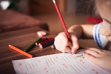 enfant tenant un crayon en train de dessiner ou faire ses devoirs