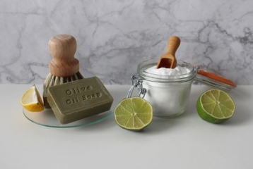 pot avec bicarbonate, demi-citrons, brosse en bois et savon à l'huile d'olive