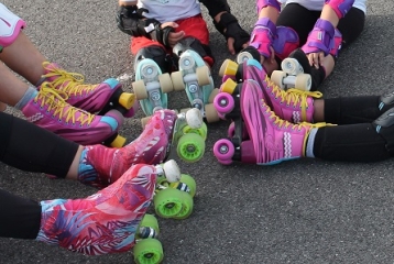 jambes d'enfants qui portent des patins à roulettes roses