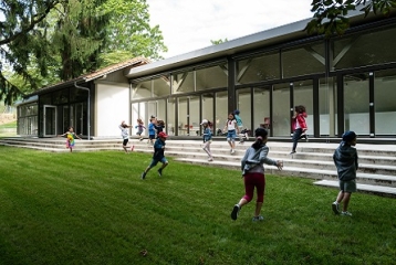 enfants qui jouent sur l'herbe devant un grand bâtiment