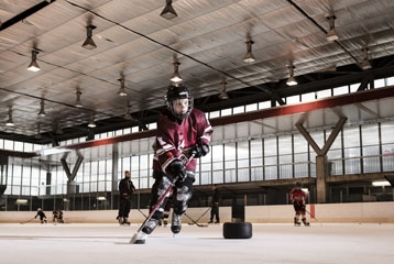 Jeune personne en habits de hockey sur glace qui tient une canne
